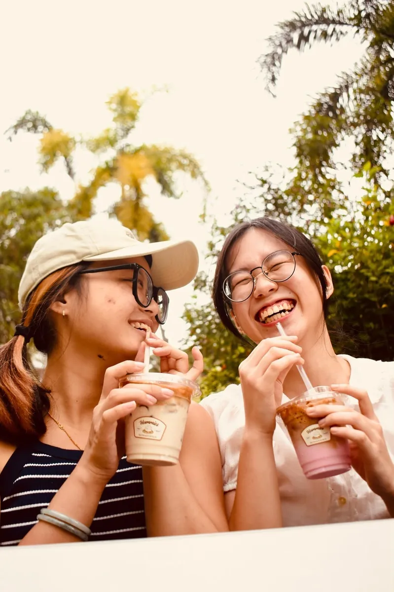 Two girls laughing with their drinks outdoors